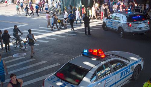 Photo shows a busy intersection with three police vehicles and two police officers directing traffic. 