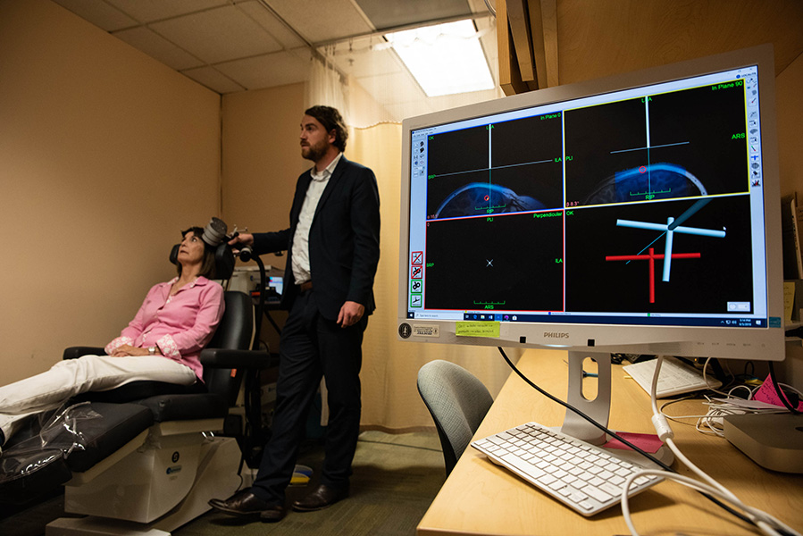 Photograph of neuroscientist Nolan Williams holding TMS device to a study participant’s head.