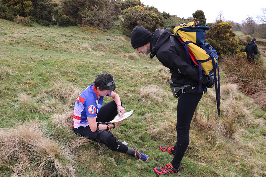 Two people peer at a map in a wilderness setting